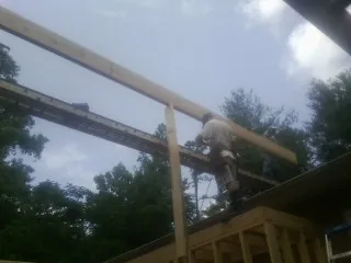 Carpenter setting a ridge beam over a new addition frame — Ice Dam Removal by Roofing Brothers in Byars