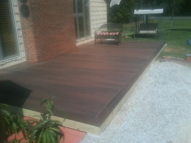 Freshly stained wood deck built against a brick home in Byars