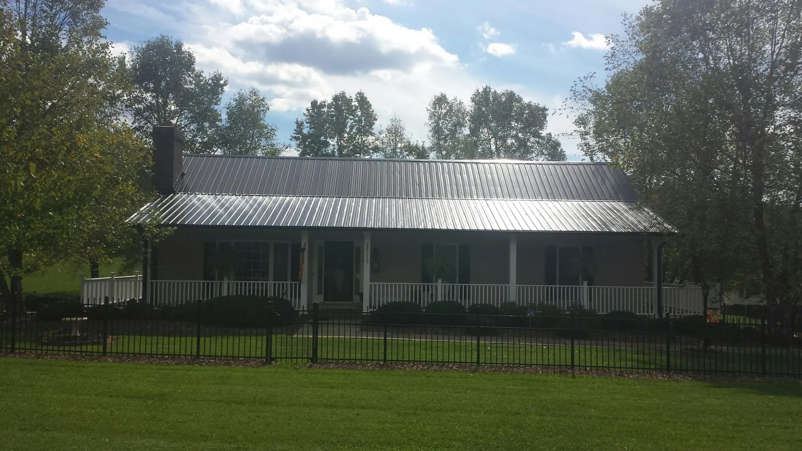 Gray metal roof on a brick ranch with a full width front porch — Gutter Guard Installation work by our crew in Byars
