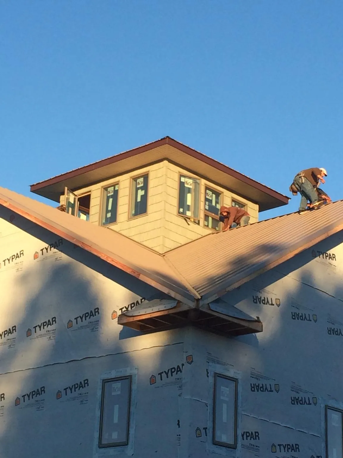 Roofers working around a rooftop cupola on a new metal roof at sunset — Roof Waterproofing in Byars by Roofing Brothers